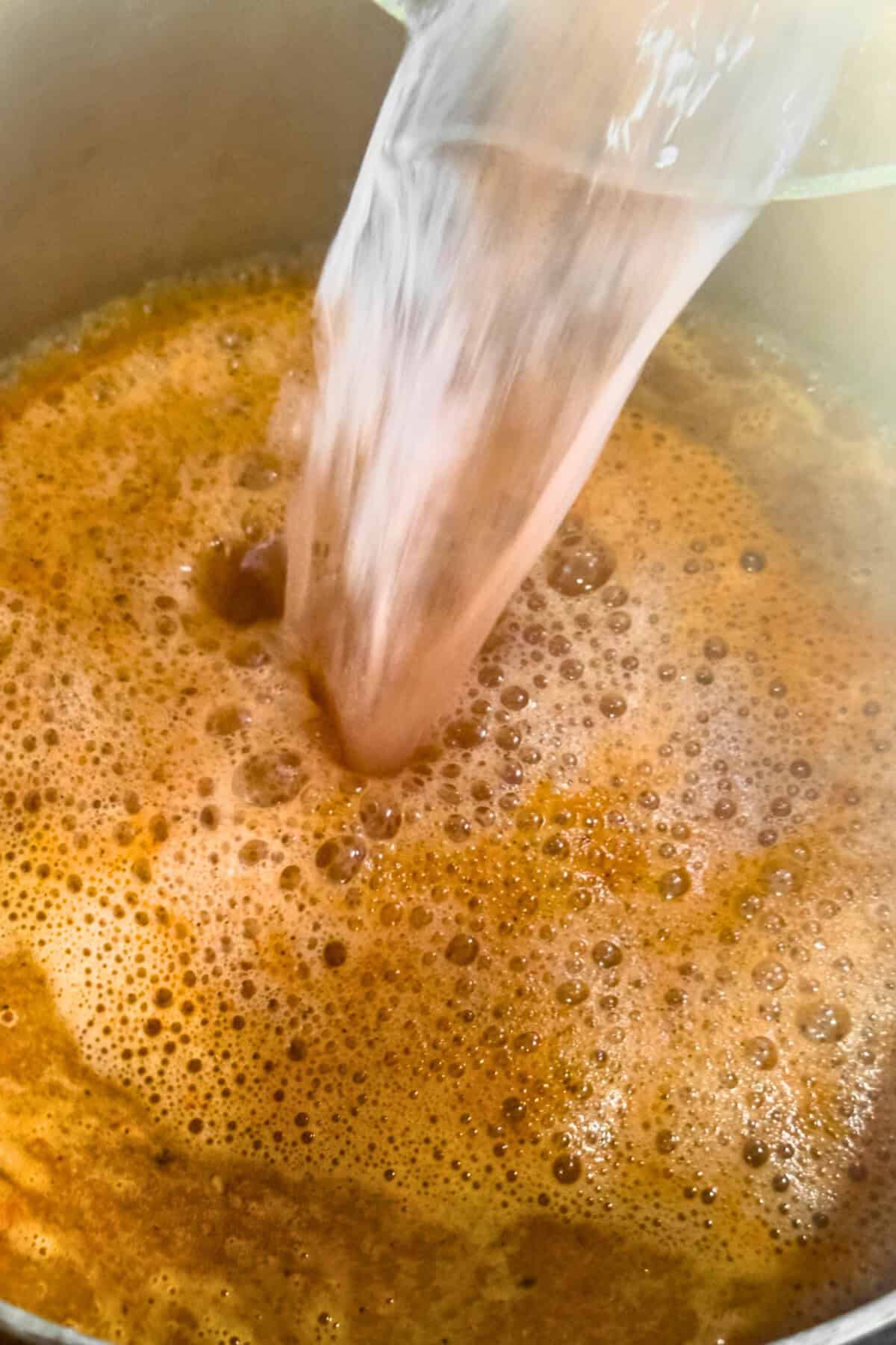 Water pouring into a pan with toasted seasoned rice.