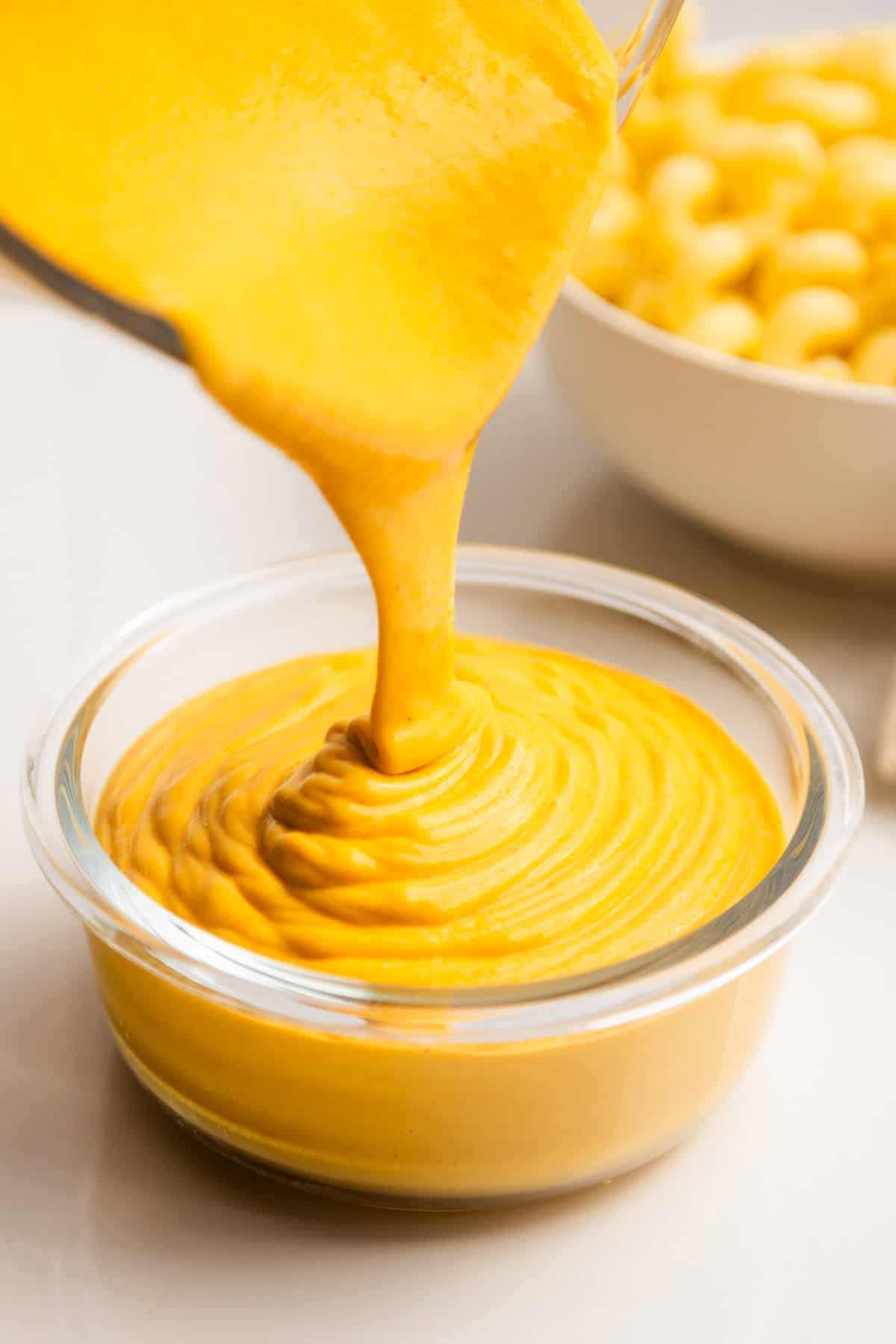 Vegan cheese sauce pouring into a bowl.