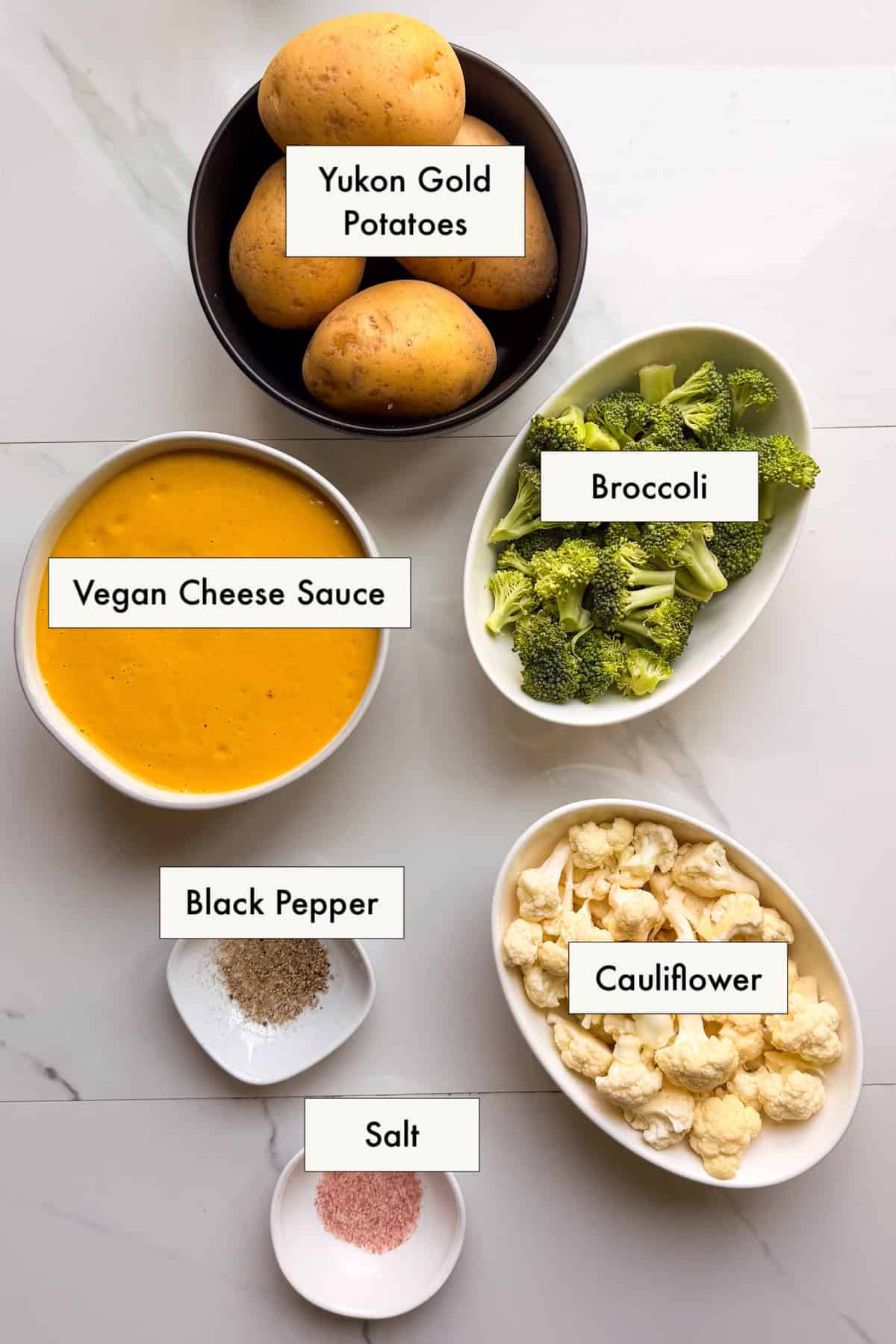 Ingredients for vegan cheesy broccoli and cauliflower and potatoes laid out on a counter.