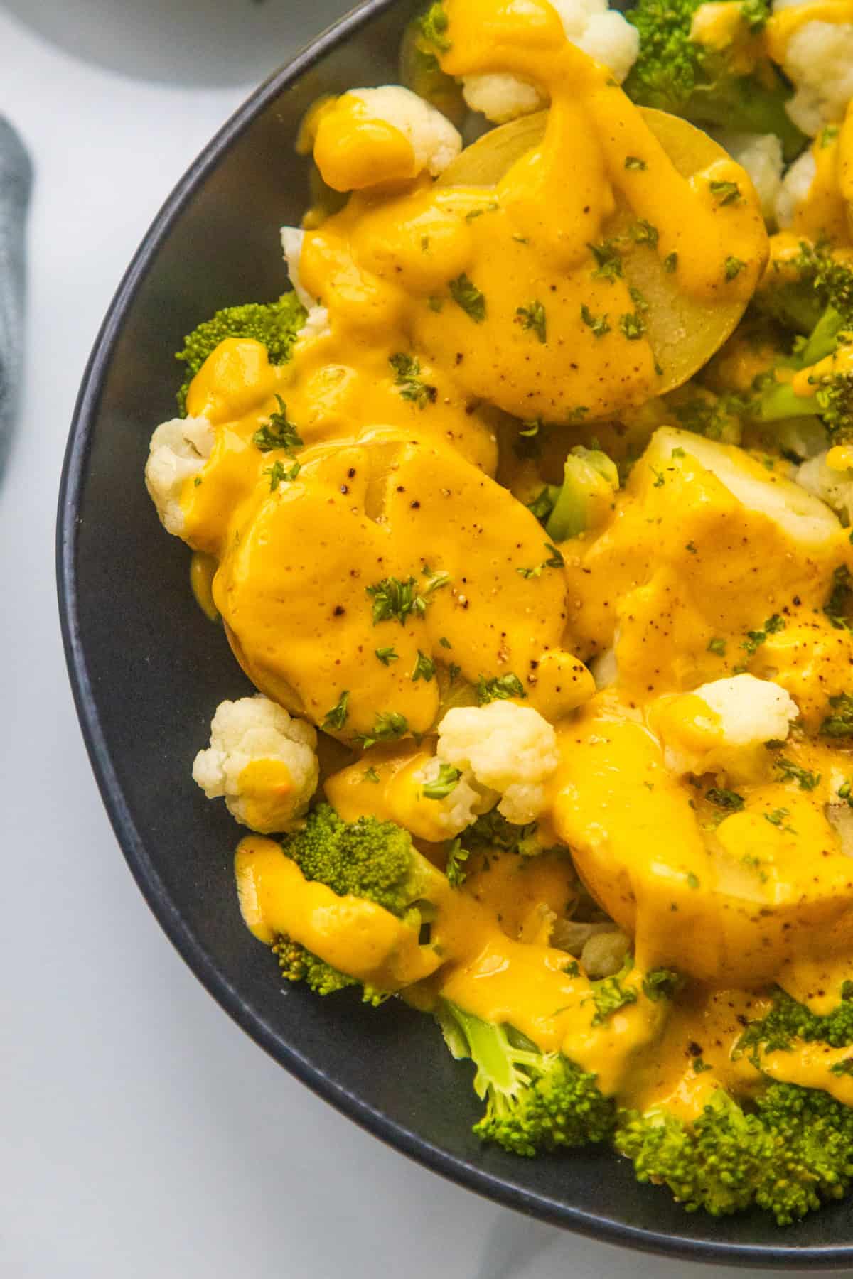Vegan cheesy broccoli and cauliflower potatoes in a black bowl.
