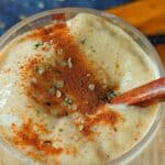 Peachy Cream Oat Smoothie in a glass topped with various seeds.