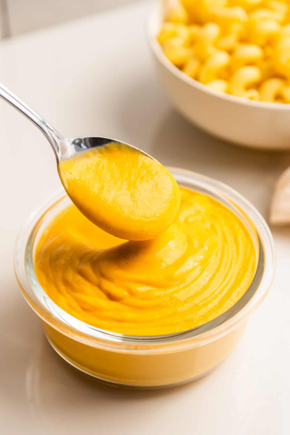 A spoon dipping into vegan cheese sauce.