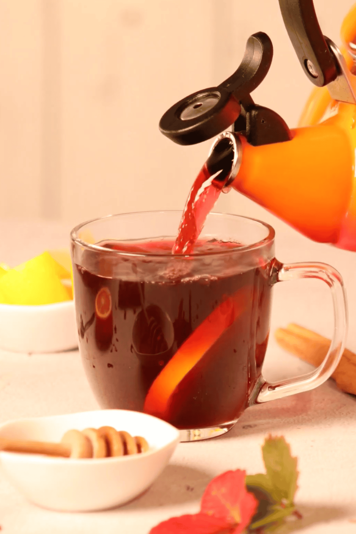 Hot hibiscus tea pouring into a glass from a tea kettle.