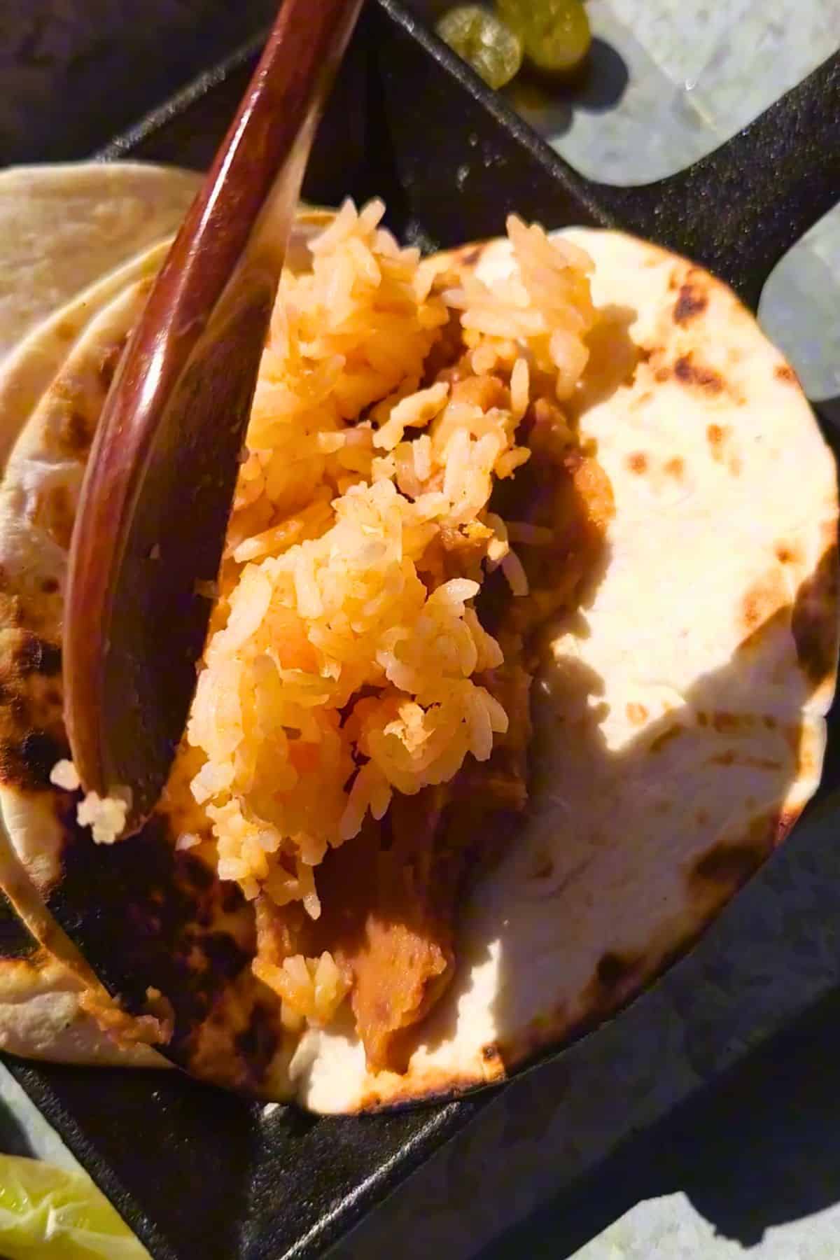 Mexican rice scooping onto a tortilla.