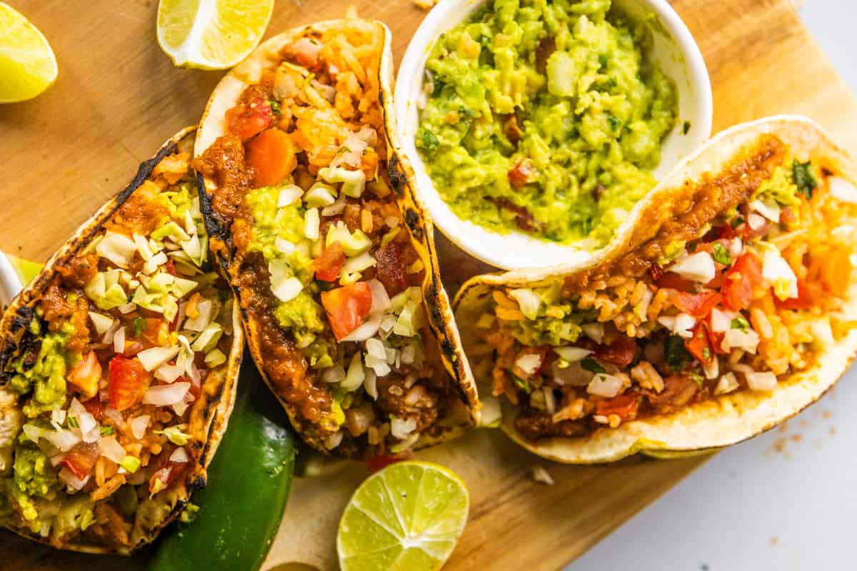 Tacos with refried beans and tacos on a wooden board.