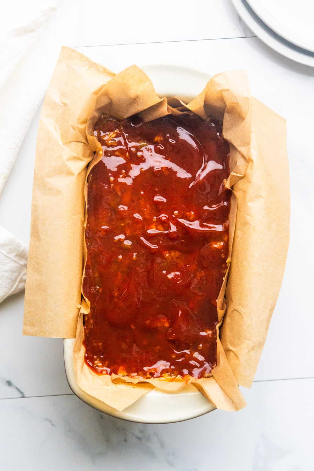 Unbaked lentil meatloaf loaf mixture in a parchment-lined loaf pan.