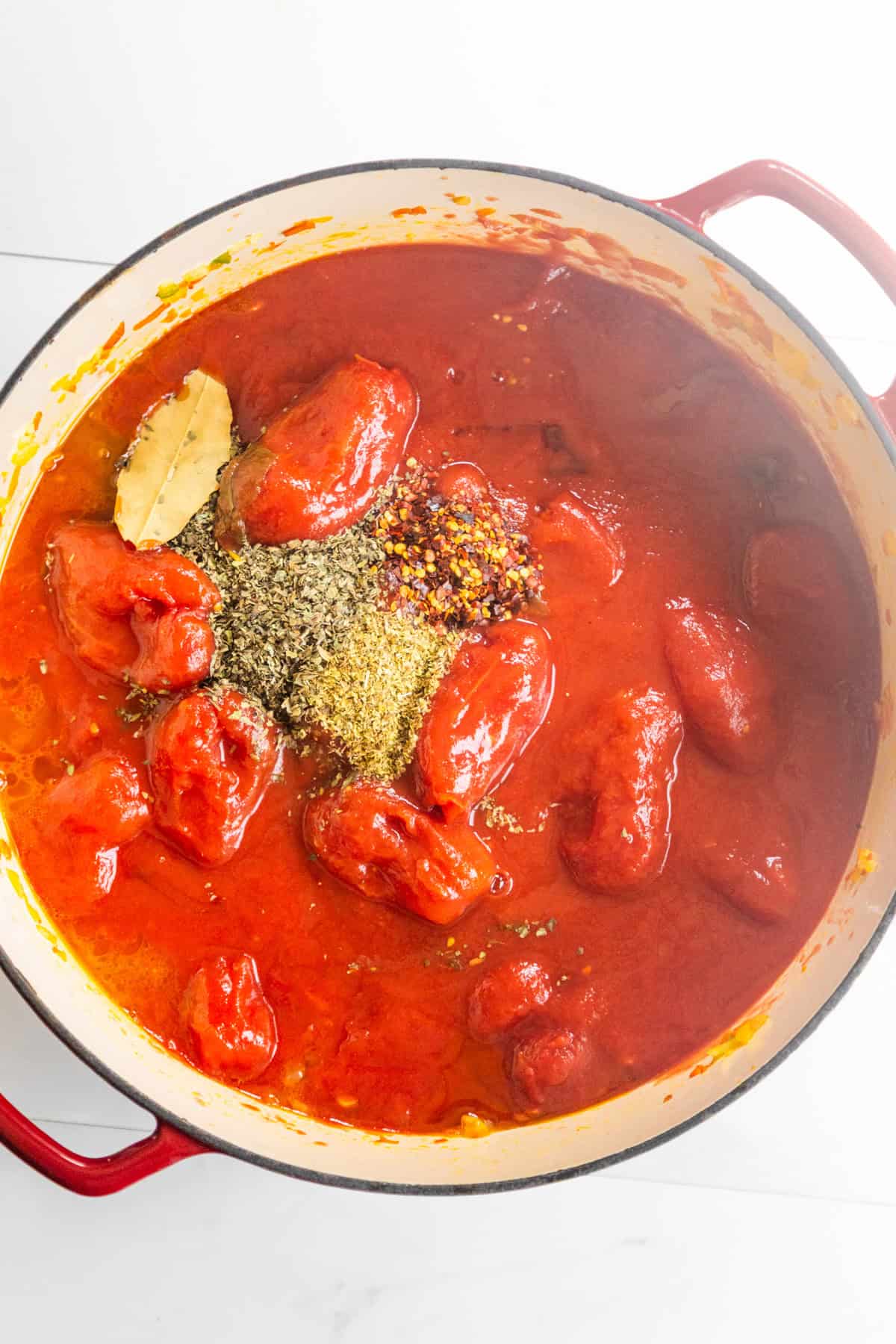 Tomatoes and other ingredients cooking in a dutch oven.