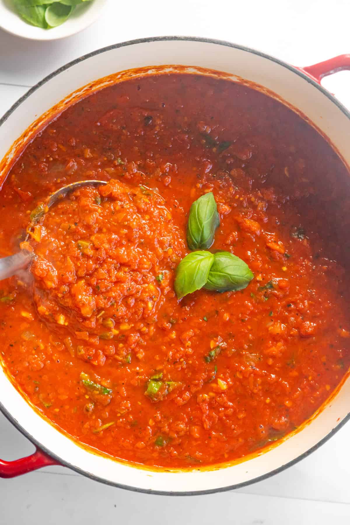 Ladle scooping up marinara sauce from a pot.
