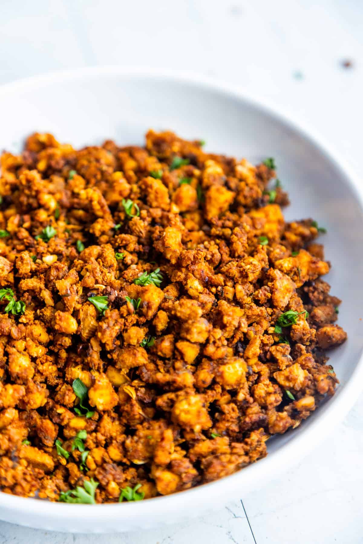 Vegan Italian Sausage Crumbles in a bowl topped with chopped fresh parsley.