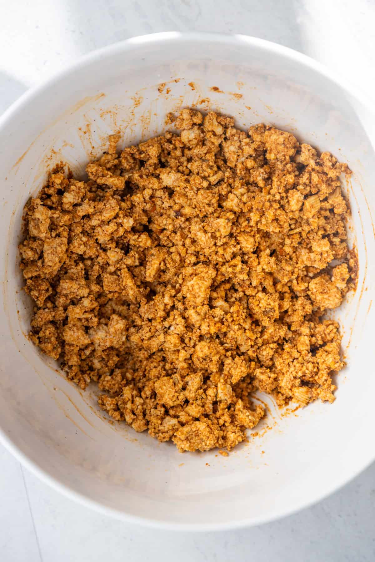 Tofu mixing with seasonings in a bowl.