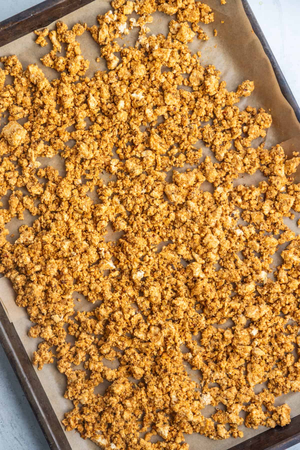 Vegan sausage crumbles spread on a baking sheet.