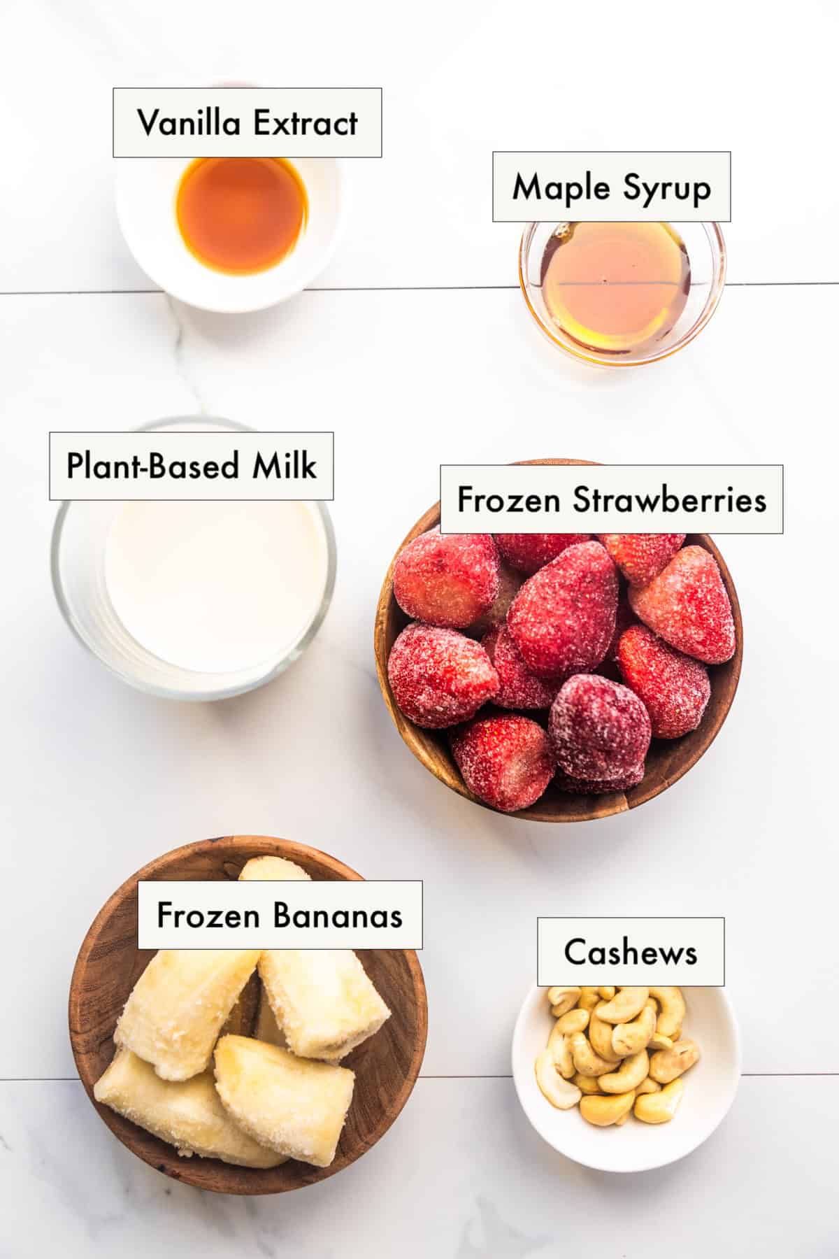 All ingredients for strawberry banana smoothie without yogurt recipe in labeled bowls.