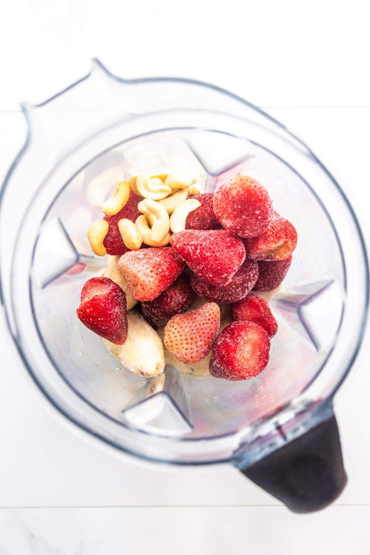 Ingredients for strawberry banana smoothie without yogurt in a blender.