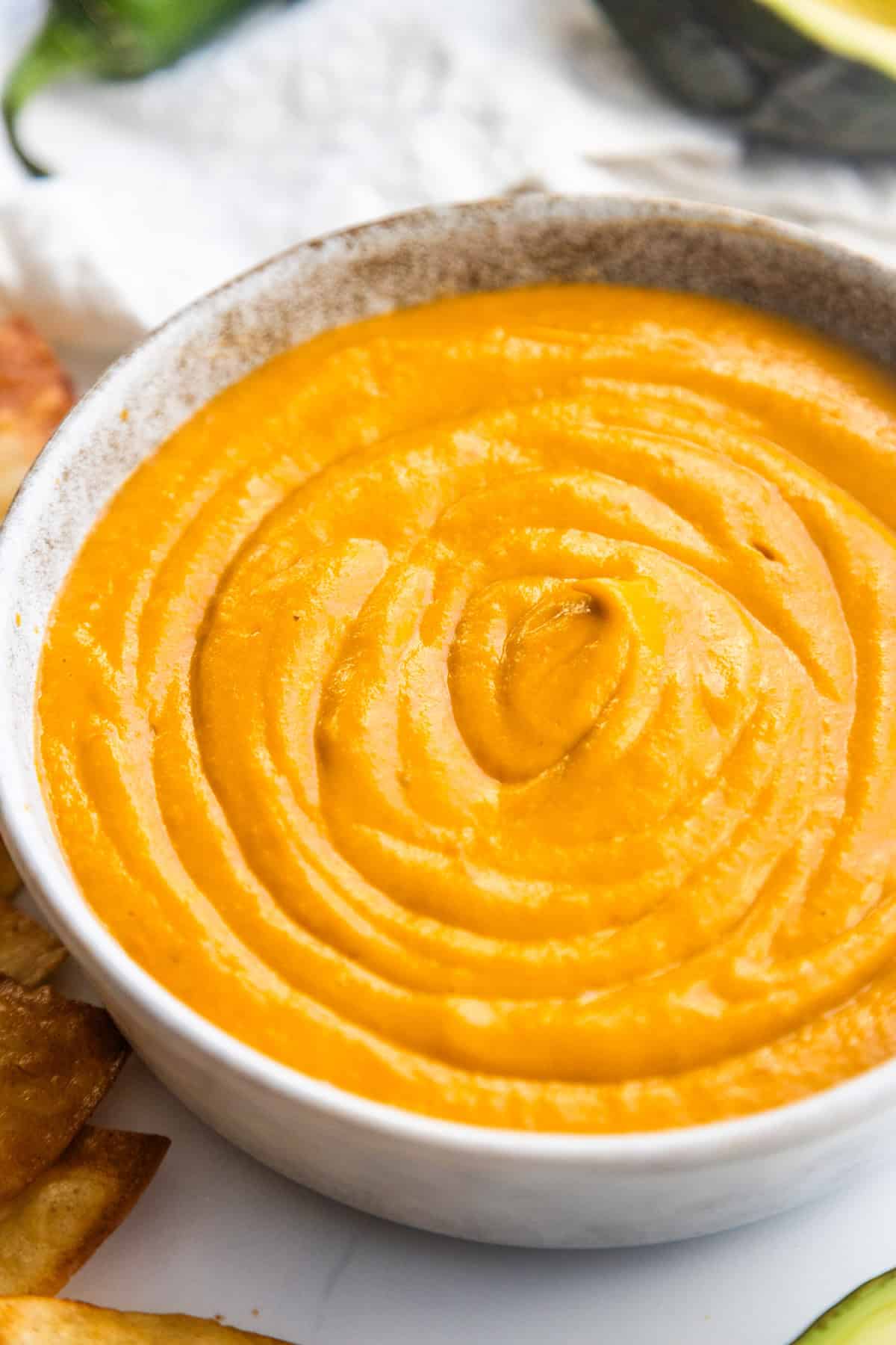 Creamy avocado tomato salsa in a bowl with chips on the side.