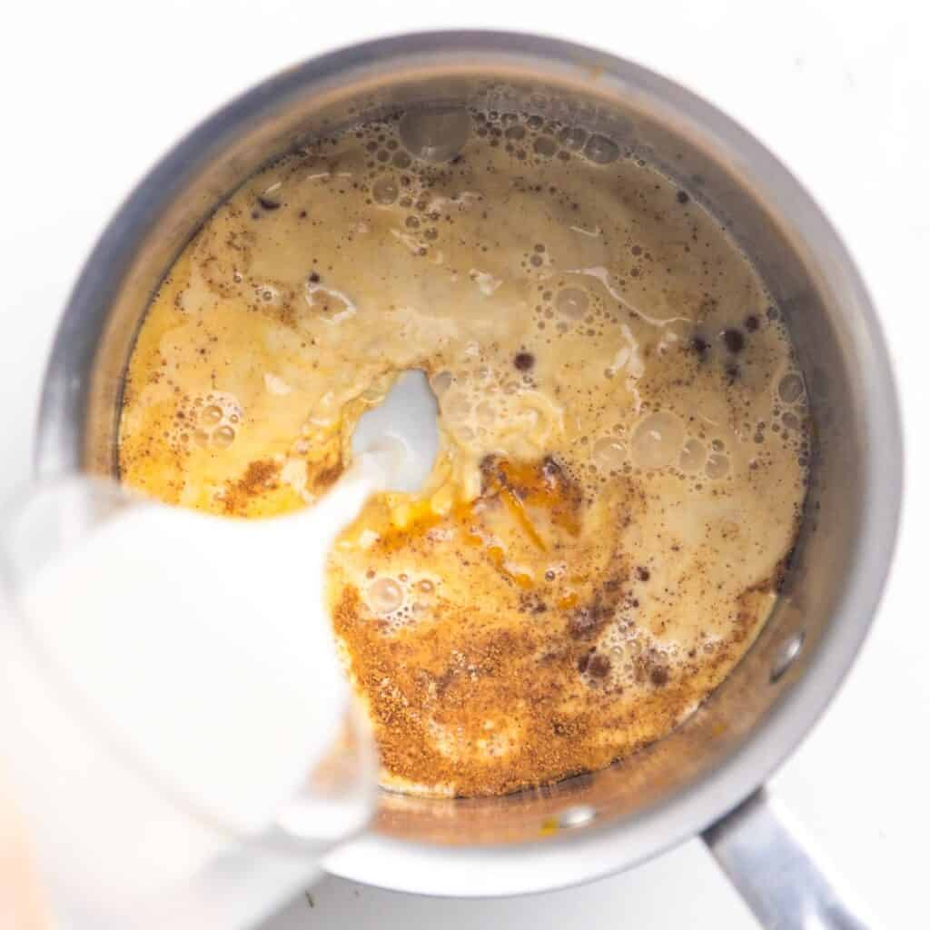 Plant-based milk, pumpkin puree, and other spices in a saucepan.