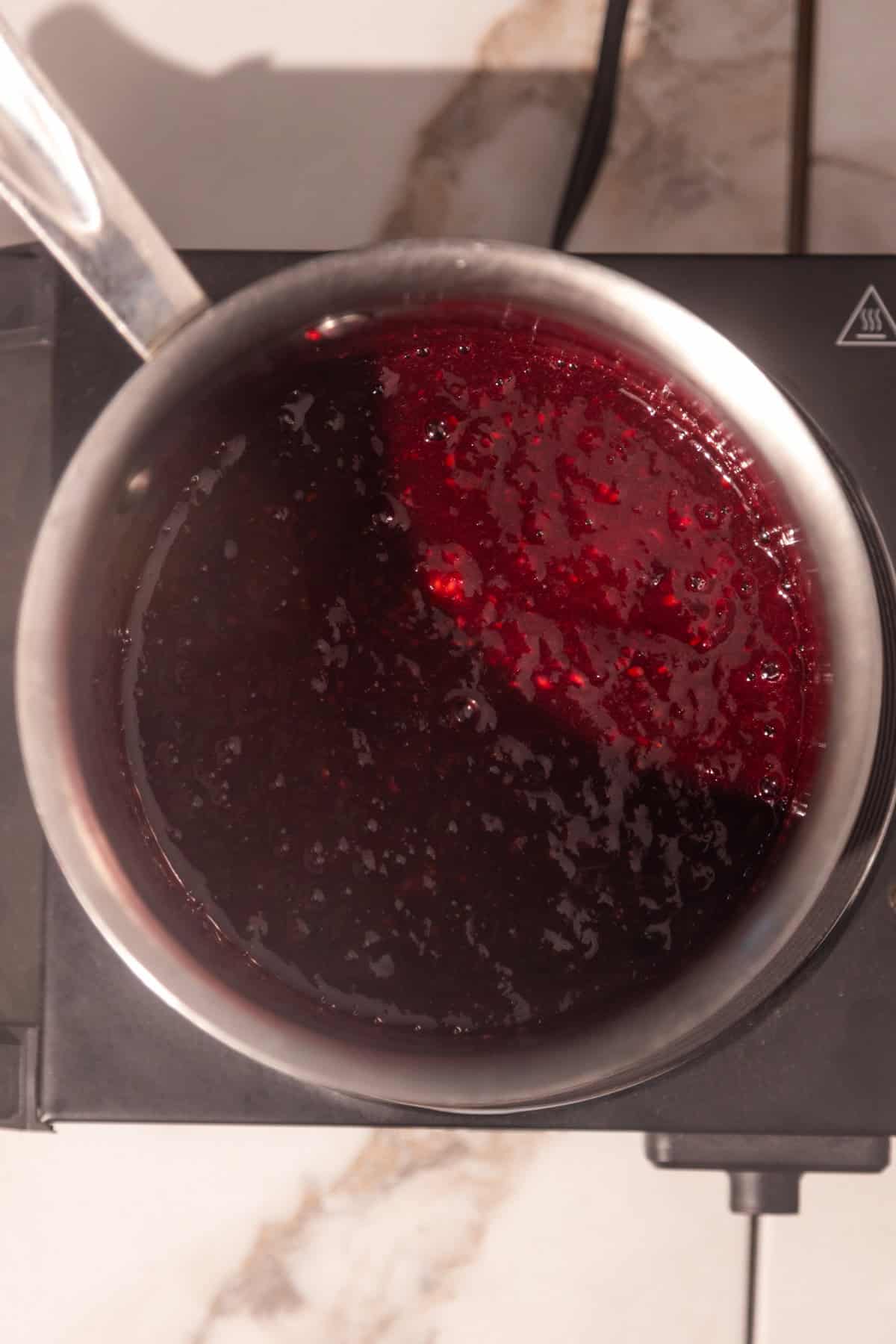 Finished berry sauce in a saucepan.