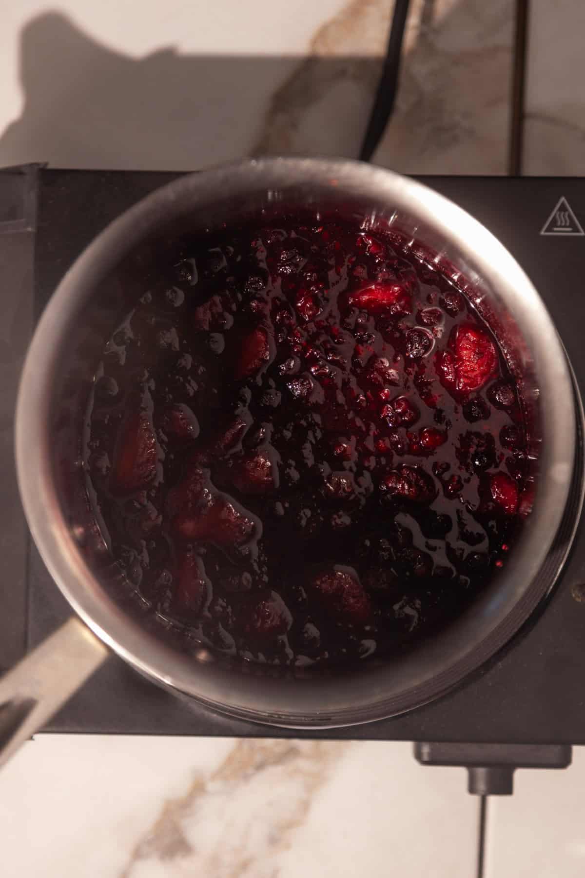 Cooked frozen berries in a saucepan.