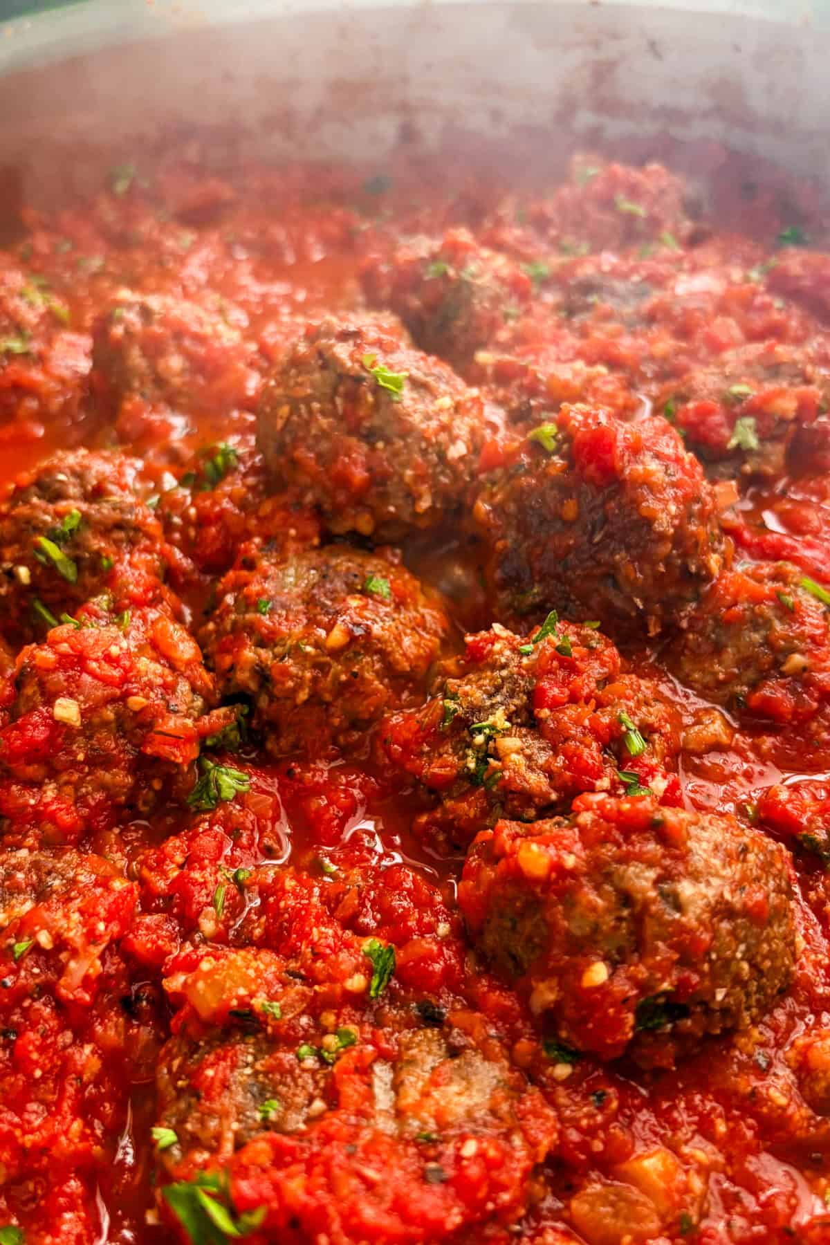 Vegan impossible meatballs topped with fresh parsley simmering in marinara sauce.