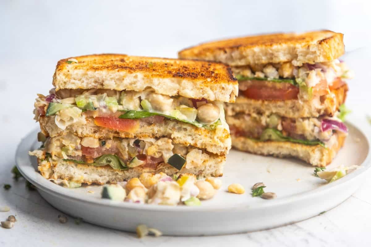 Chickpea salad sandwich sliced in half on a plate.