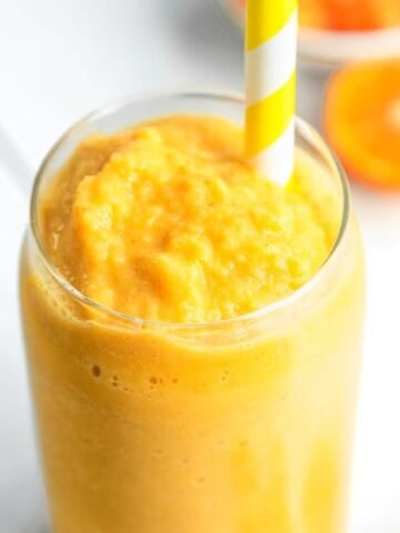 Dairy-free orange creamsicle smoothie in a glass with a yellow straw.