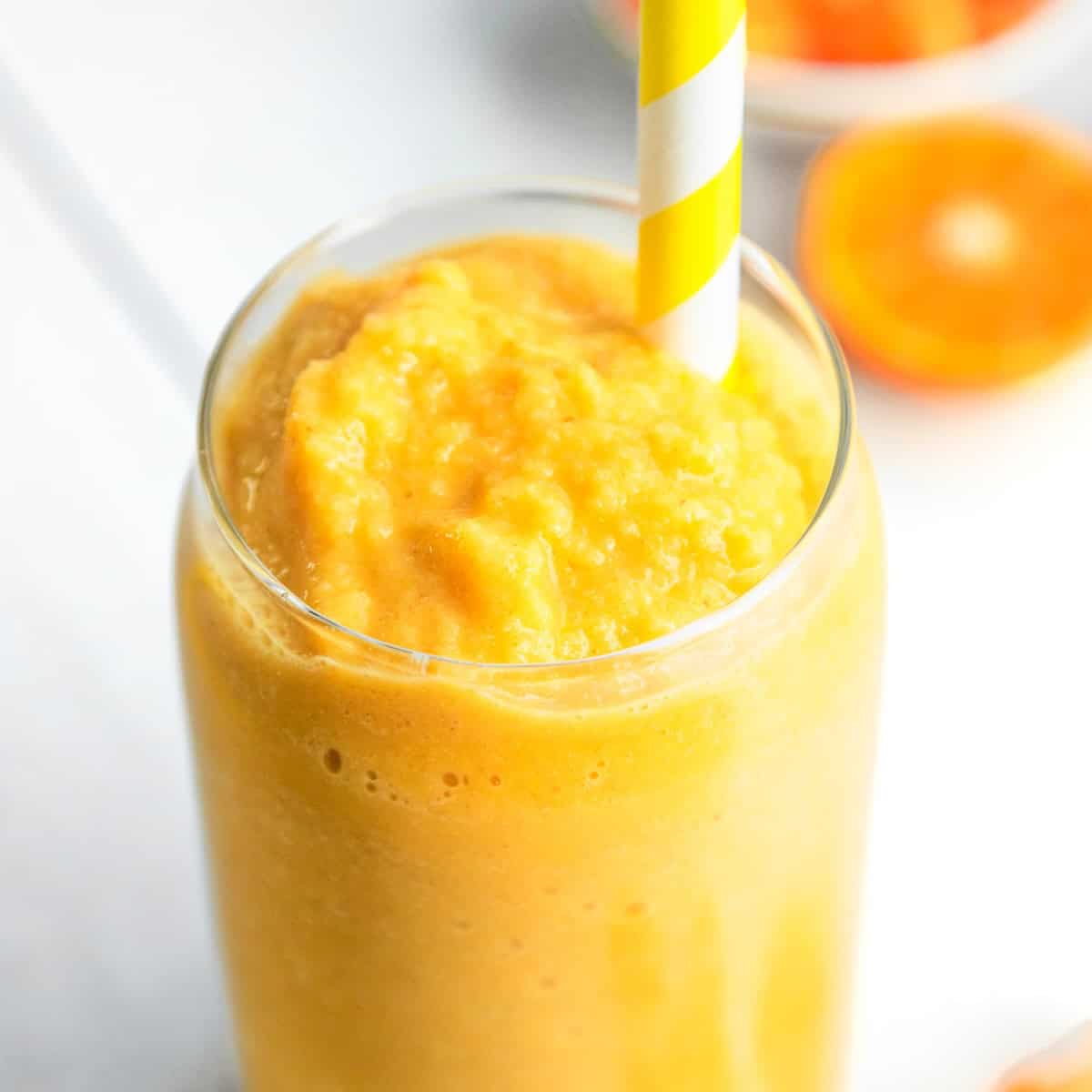 Dairy-free orange creamsicle smoothie in a glass with a yellow straw.