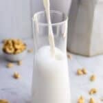 Homemade cashew milk pouring into a glass.