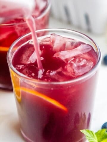 Easy blueberry lemonade recipe pouring into a glass.