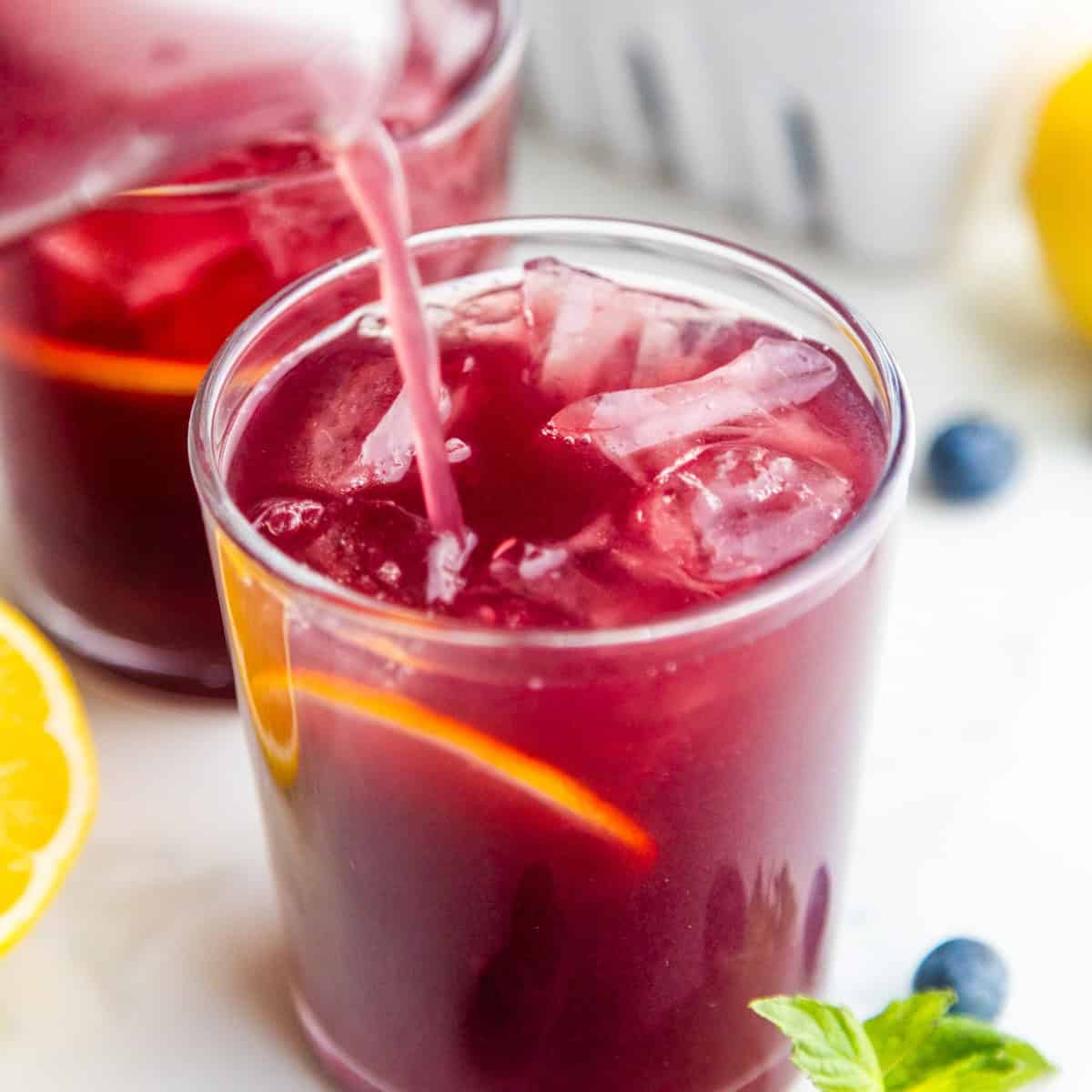 Easy blueberry lemonade recipe pouring into a glass.