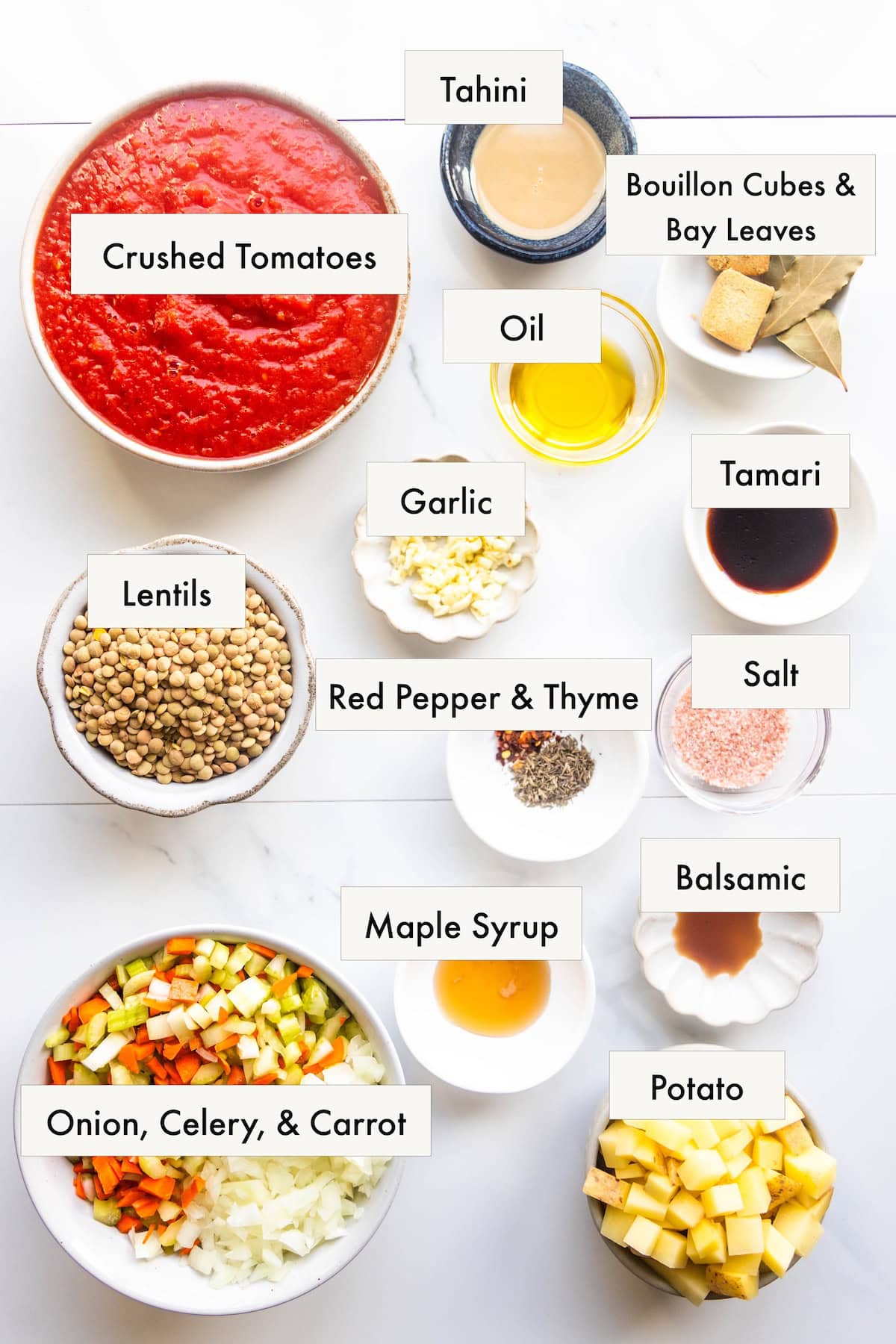 All ingredients for lentil vegetable soup in labeled bowls on a counter.