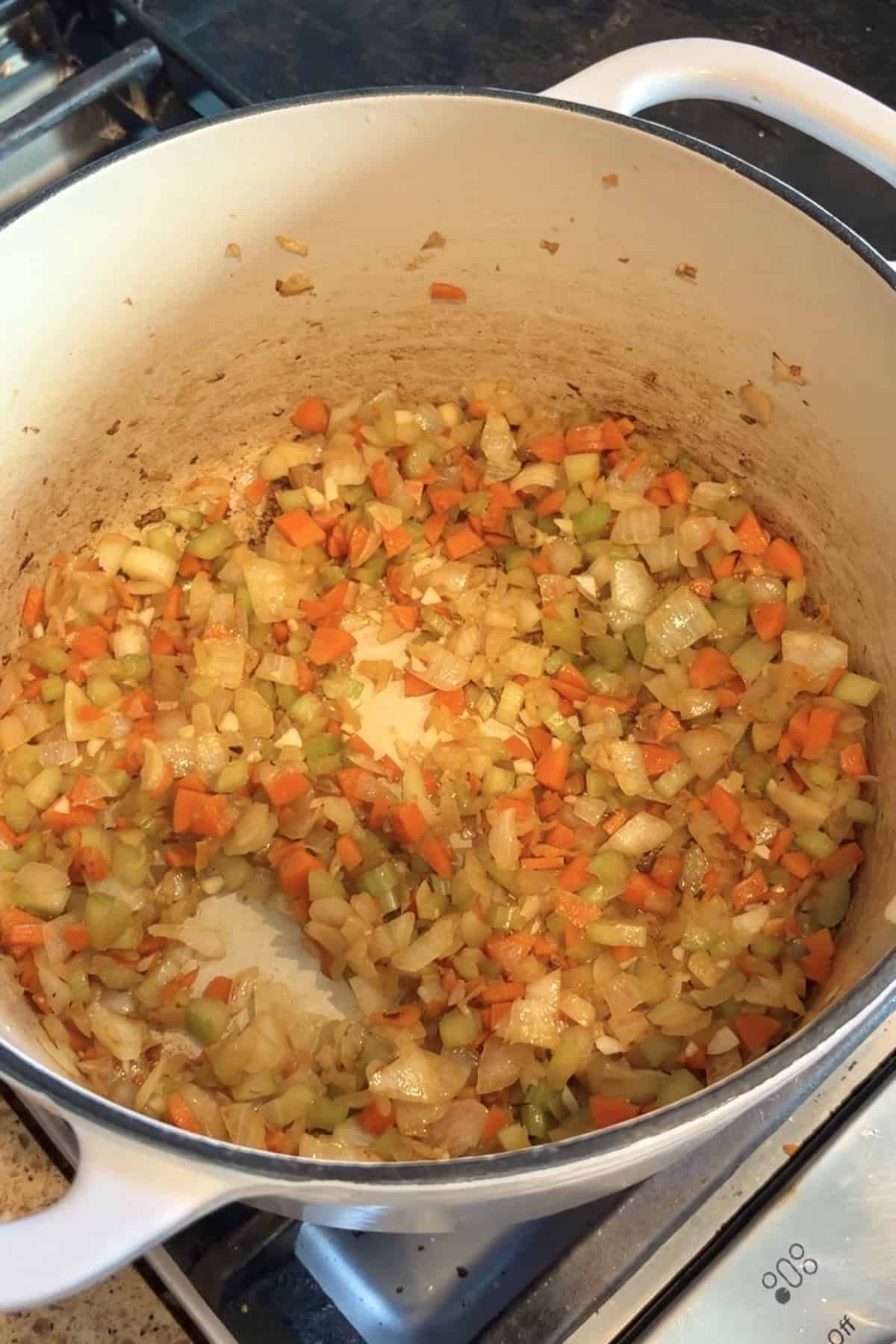 Onions, carrots, & celery sautéing in oil in a dutch oven.