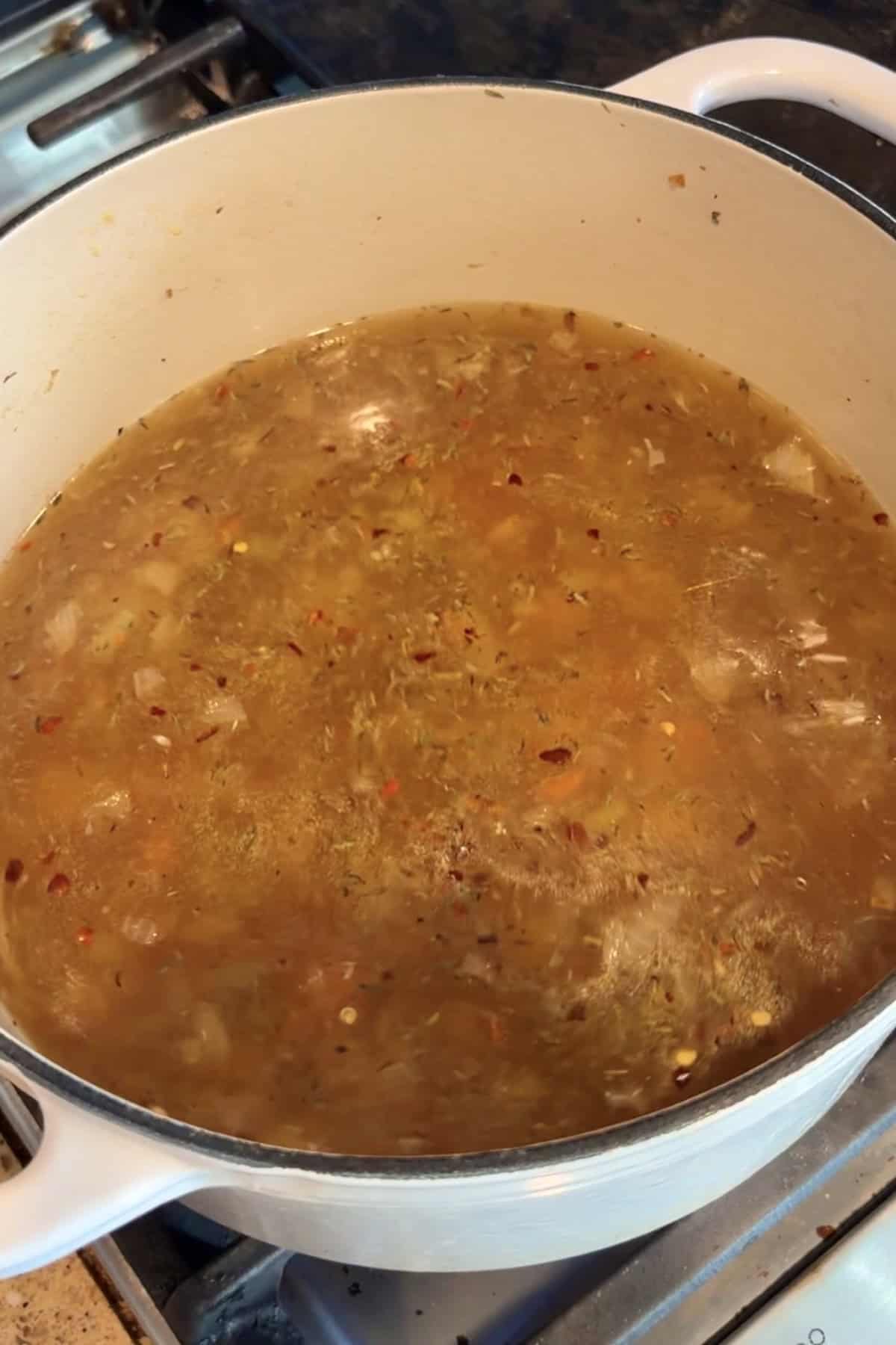 Tomato lentil soup in a dutch oven simmering on the stove.