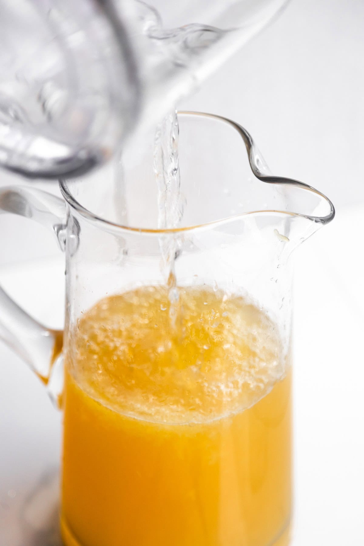 Green tea lemonade being made in a large glass pitcher.