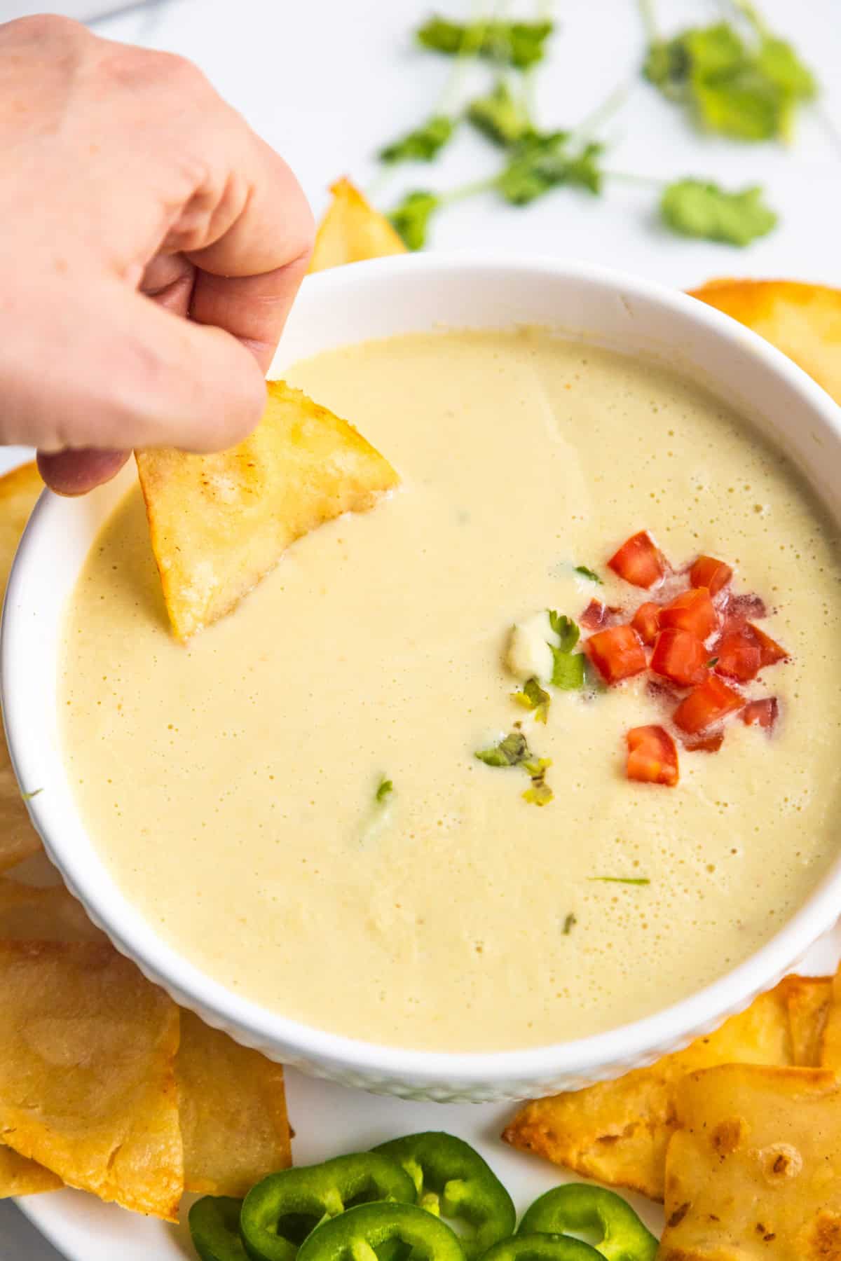 A chip dipping into creamy tomatillo salsa.