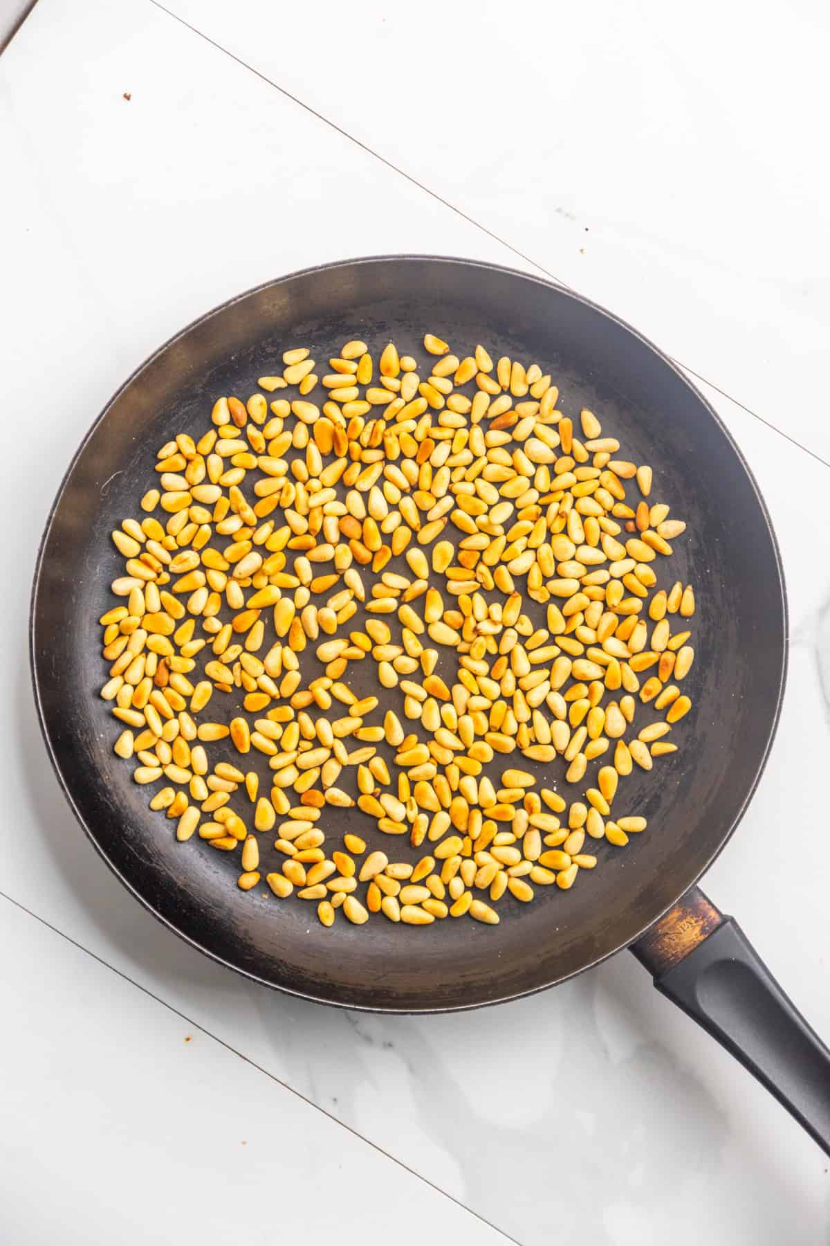 Toasting pine nuts in a pan.