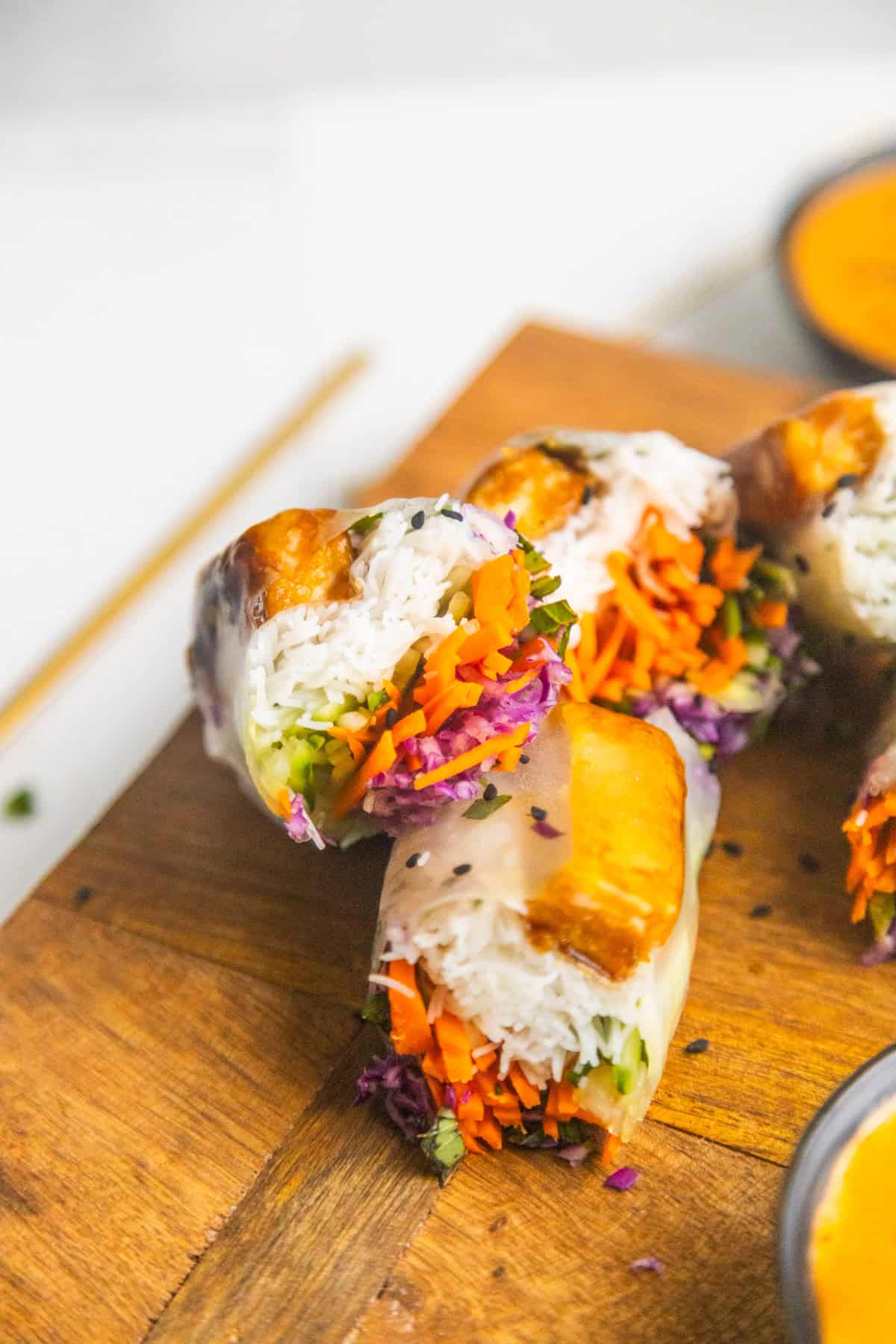 Vegan spring rolls on a cutting board sliced in half.