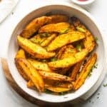 Air fryer potato wedges in a white bowl.