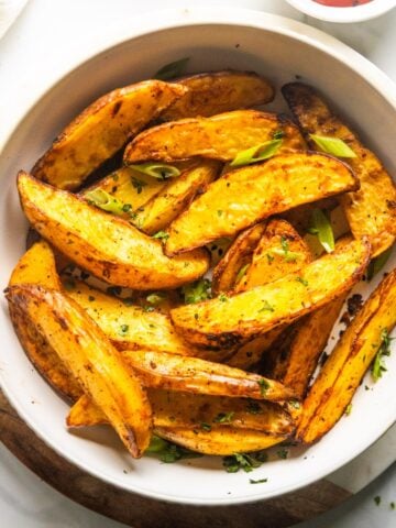 Air fryer potato wedges in a white bowl.