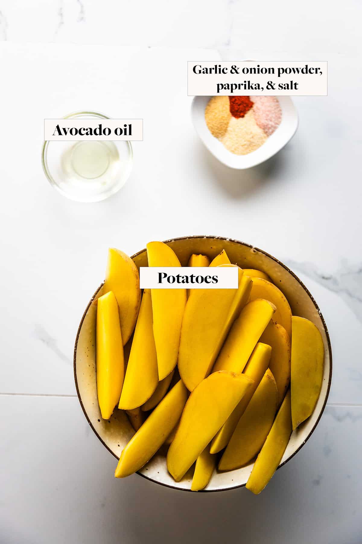 Ingredients for air fryer potato wedges in labeled bowls.