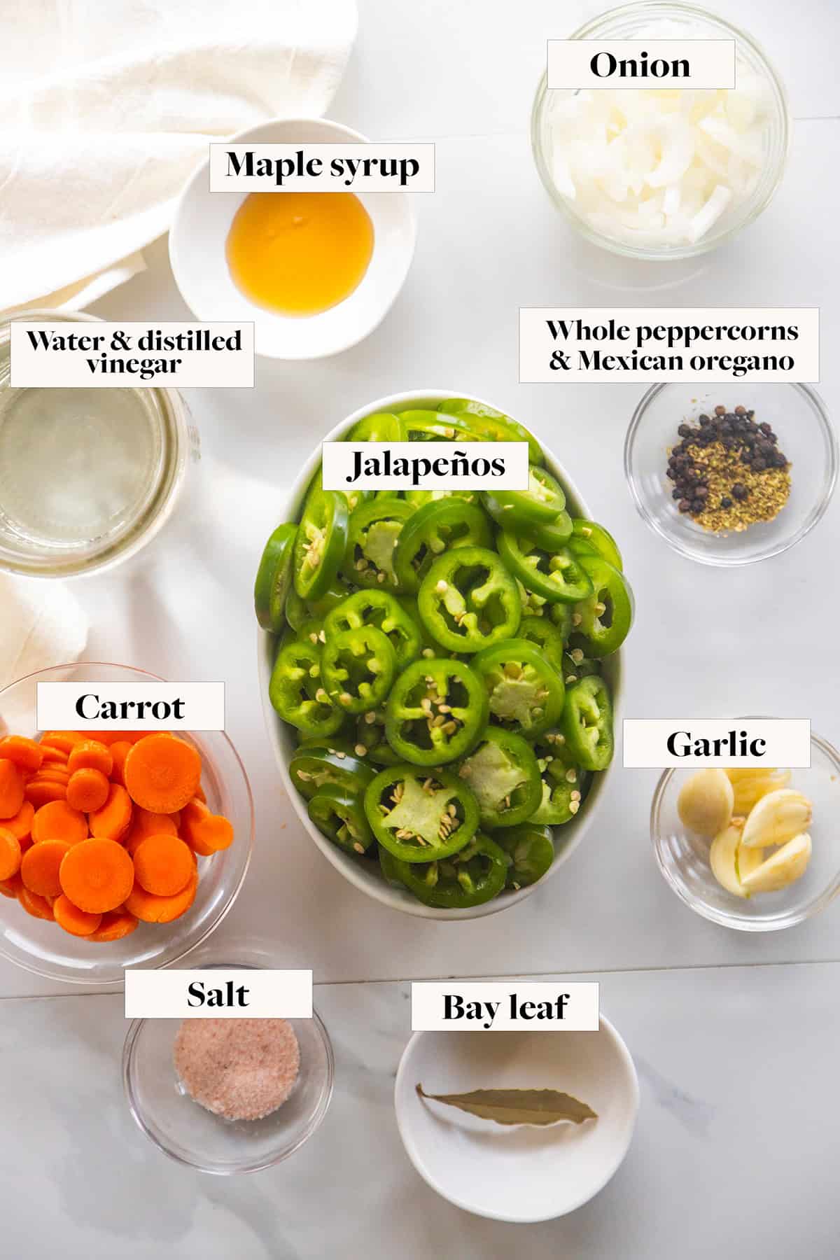 Ingredients for pickled jalapeños escabeche in labeled bowls.