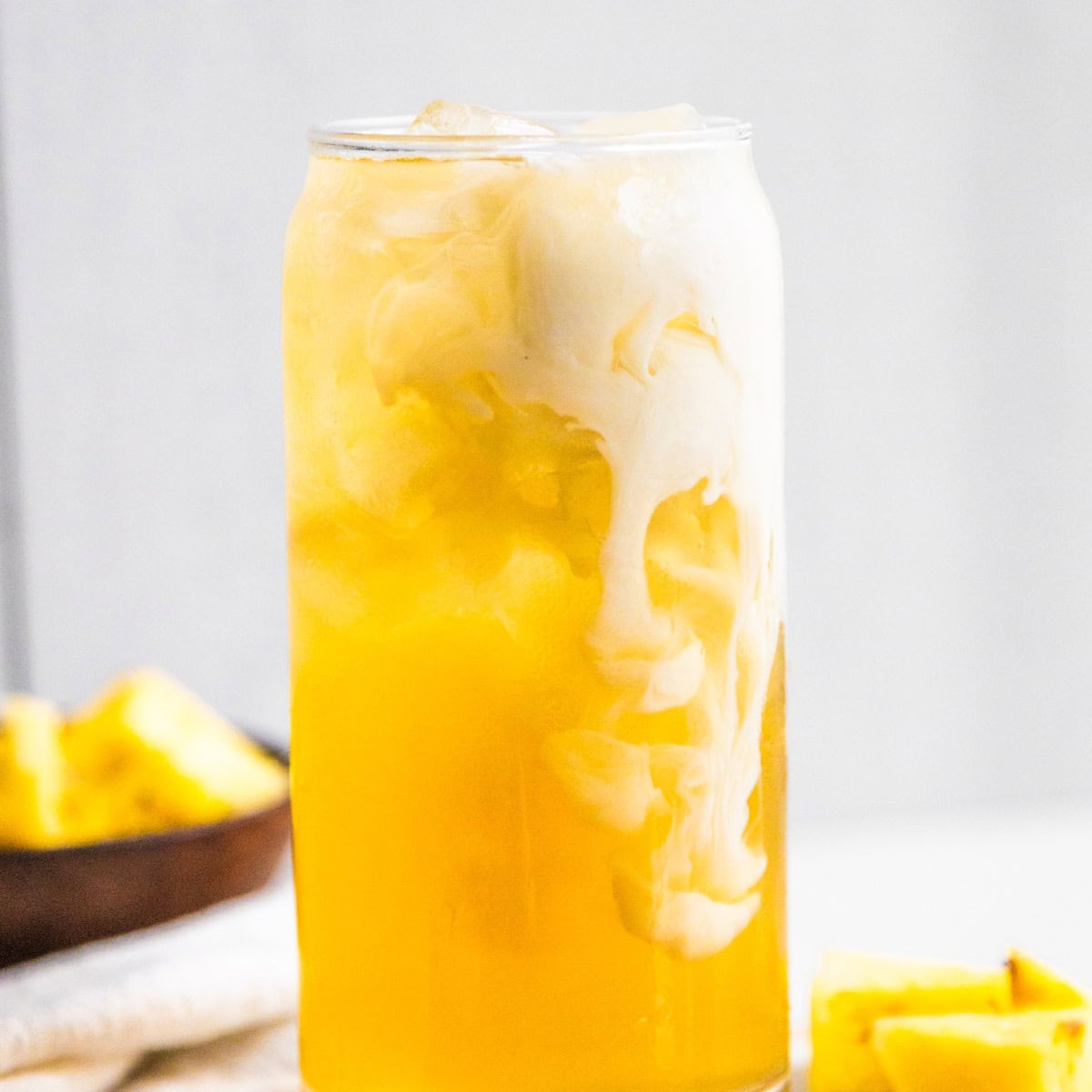 Pineapple skin tea in a glass with a splash of oatmilk.