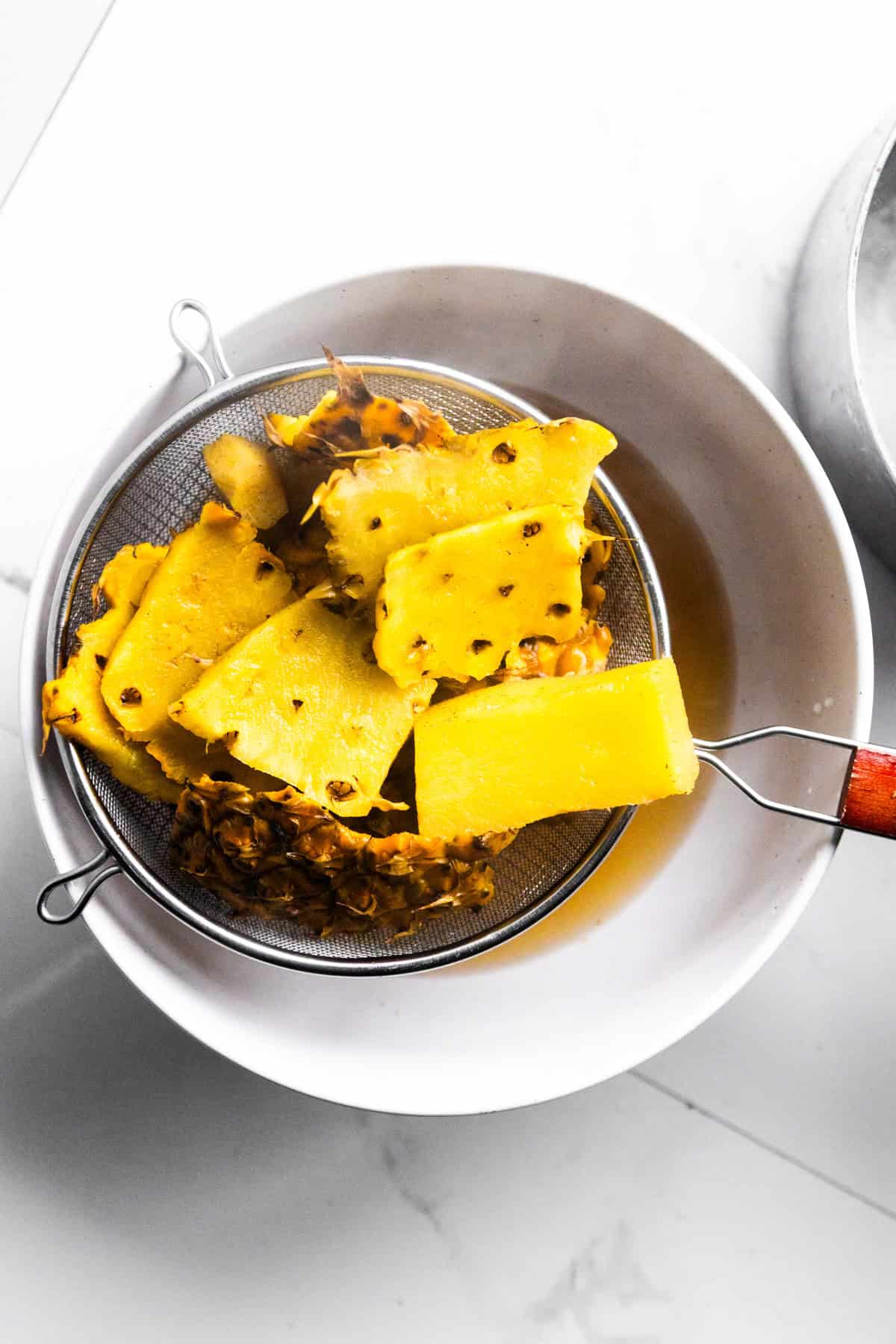 Pineapple skins tea straining into a bowl.