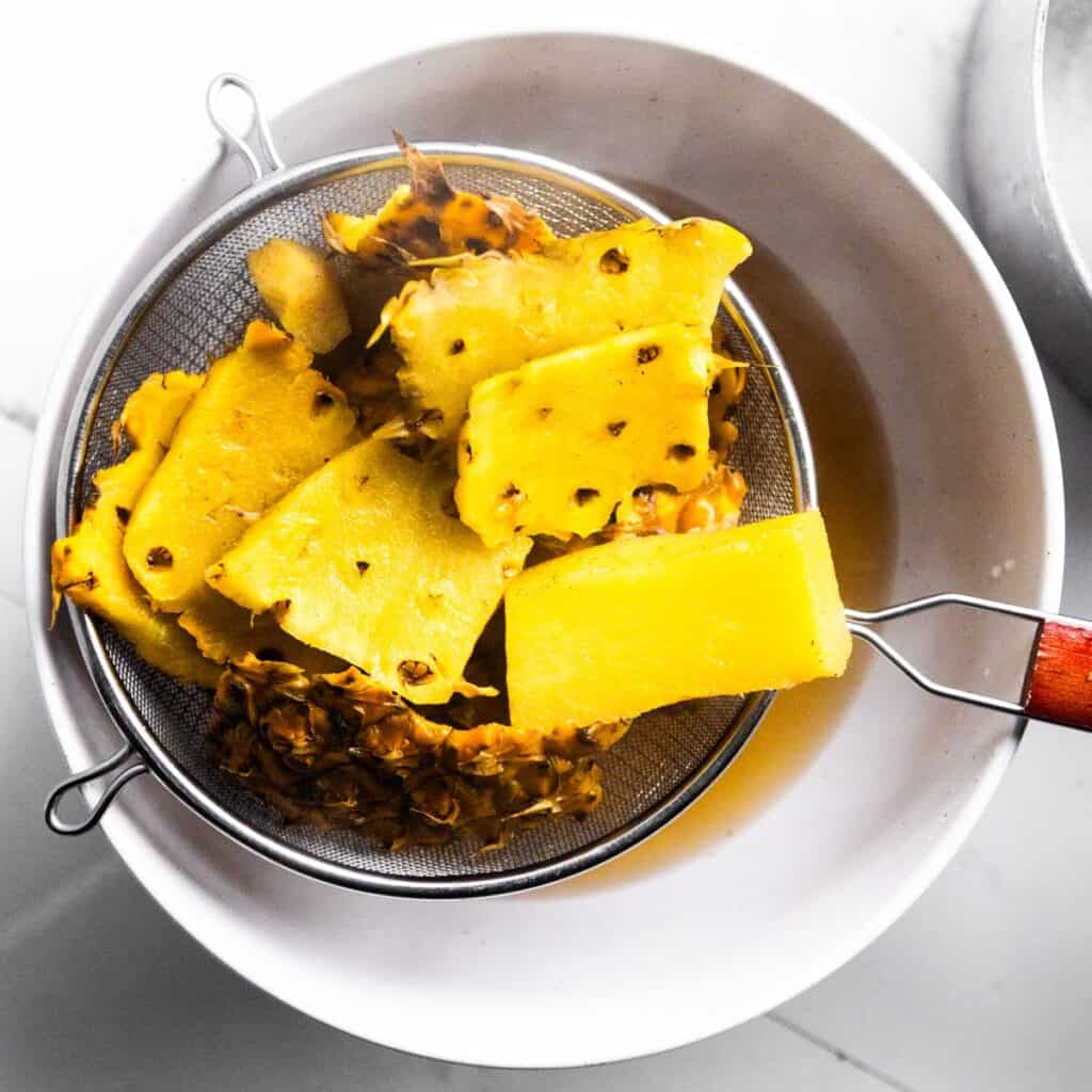 Pineapple skins tea straining into a bowl.