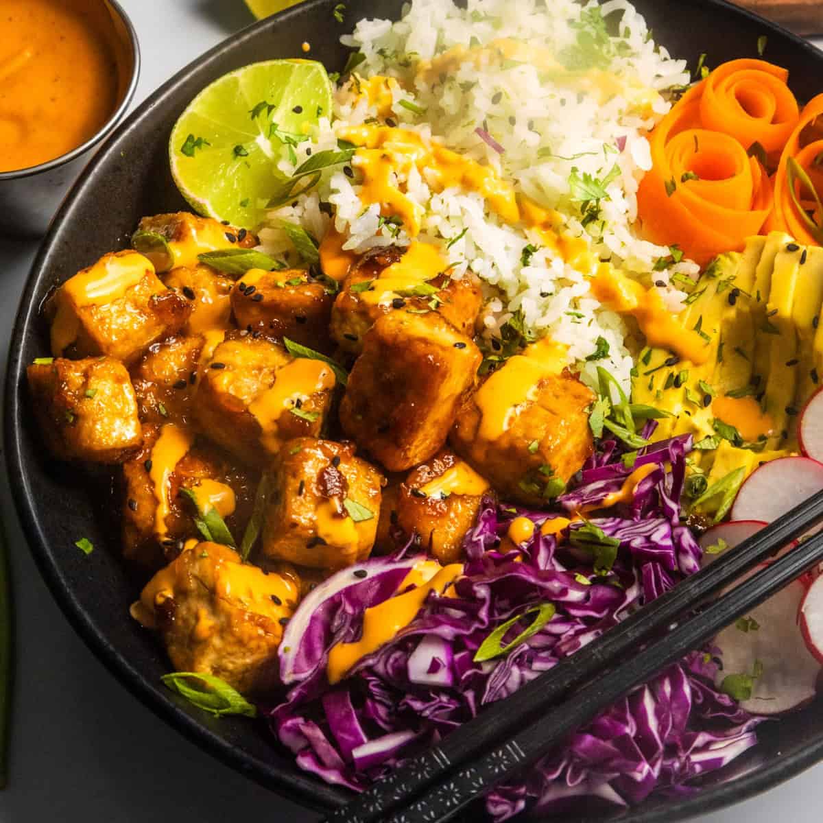 Sticky tofu bowl (AKA crispy tofu rice bowl) in a black bowl.