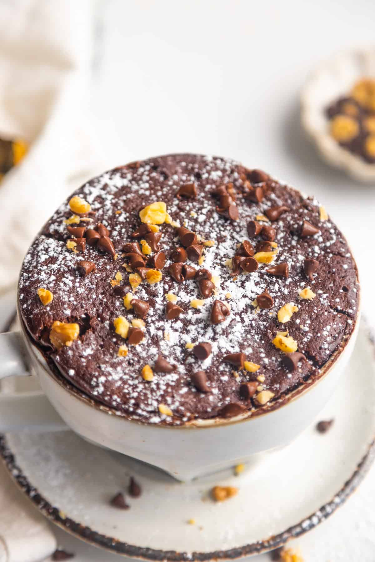 Vegan chocolate mug cake in a mug topped with powdered sugar.