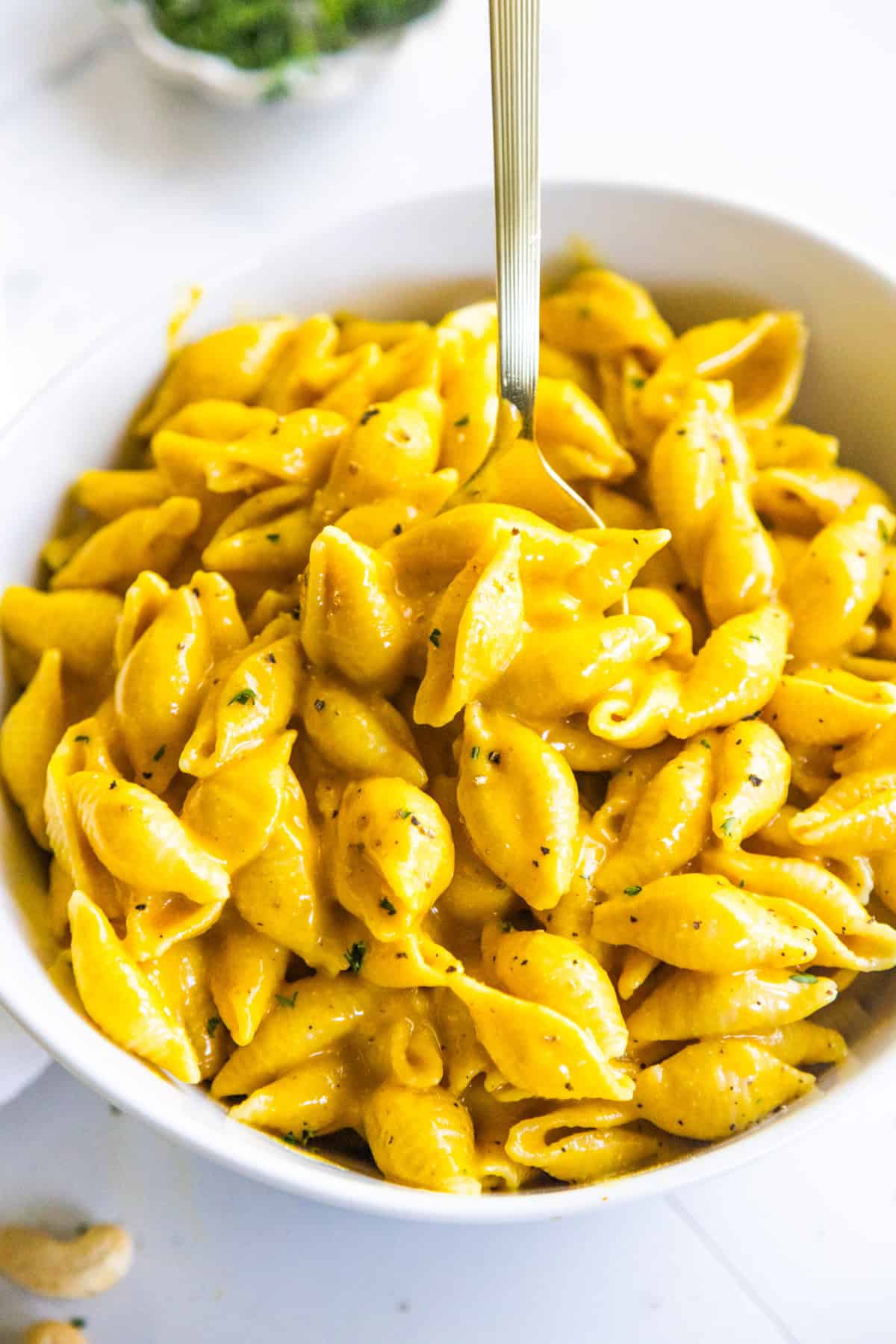 Vegan mac and cheese in a white bowl with a spoon.