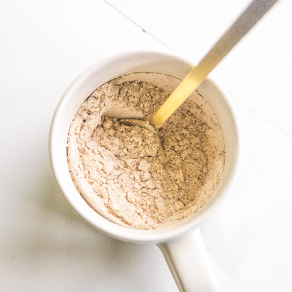 Dry ingredients for vegan pumpkin mug cake in a white mug.