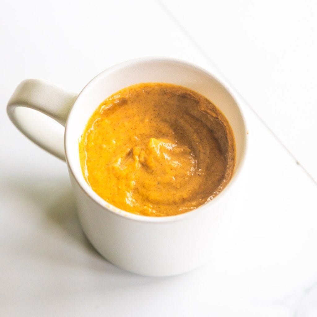 Wet & dry ingredients for vegan pumpkin mug cake in a white mug.