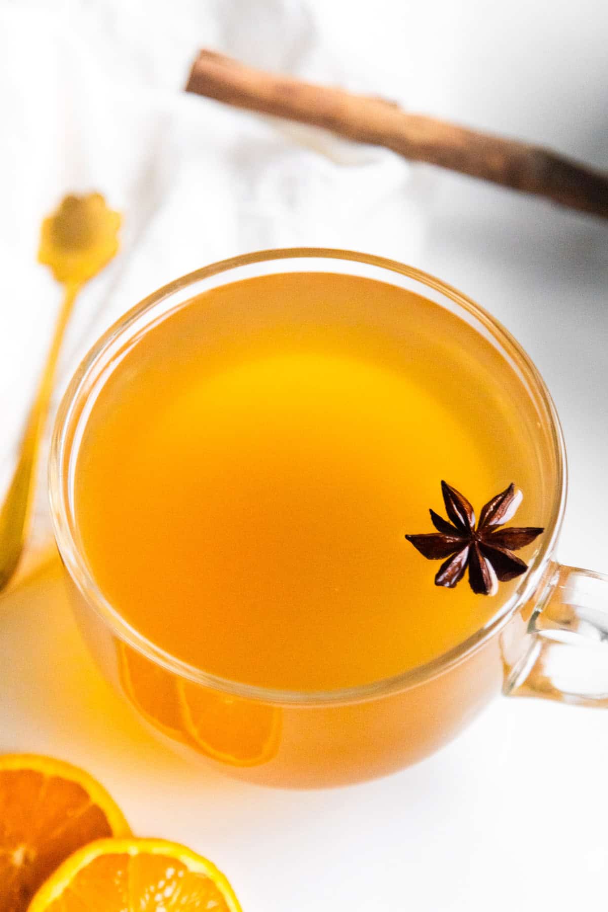 Warm pineapple skin tea in a clear mug topped with a star anise.