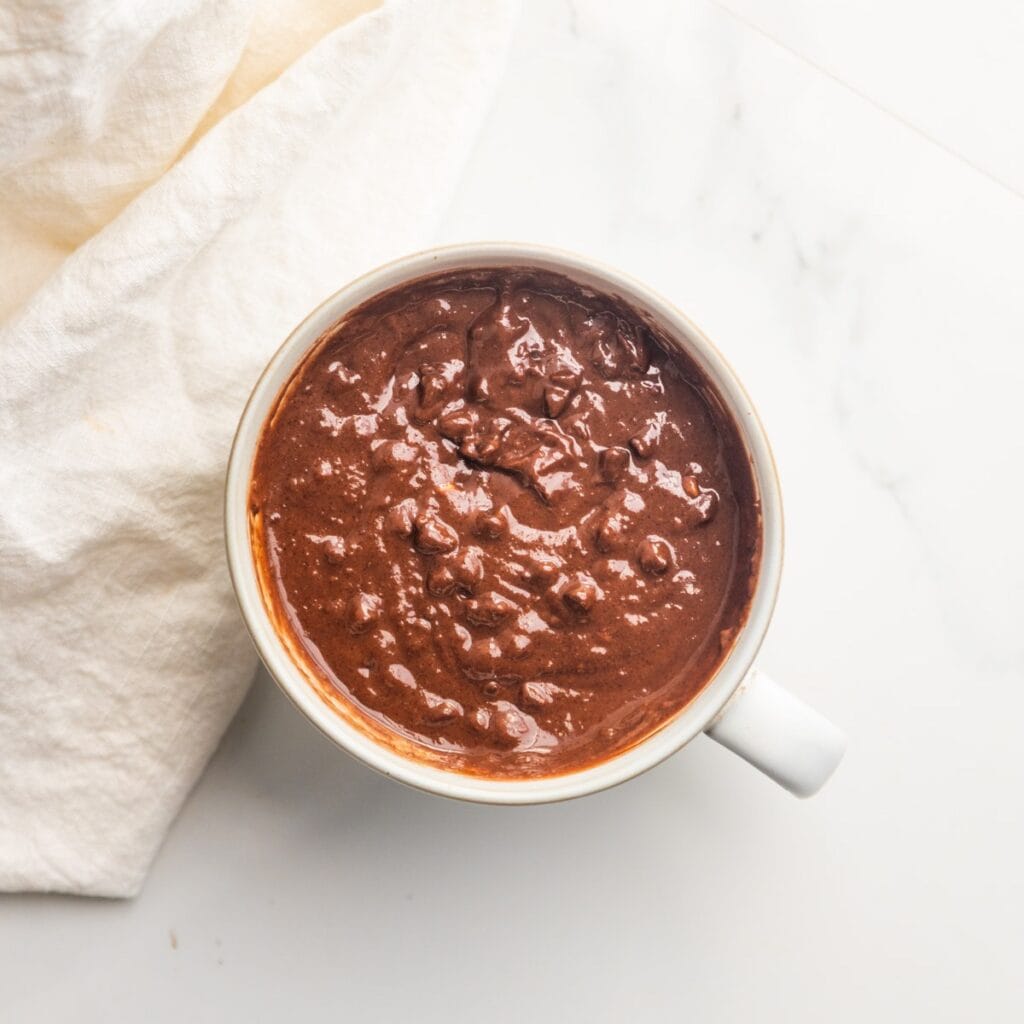Wet and dry ingredients combined in a mug for a vegan chocolate mug cake.