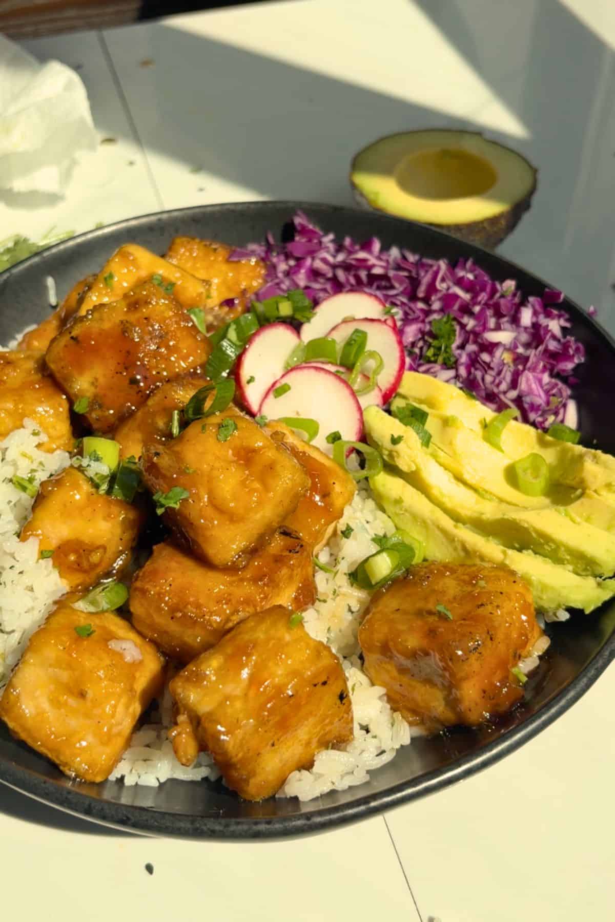White rice and tofu in a bowl with toppings.